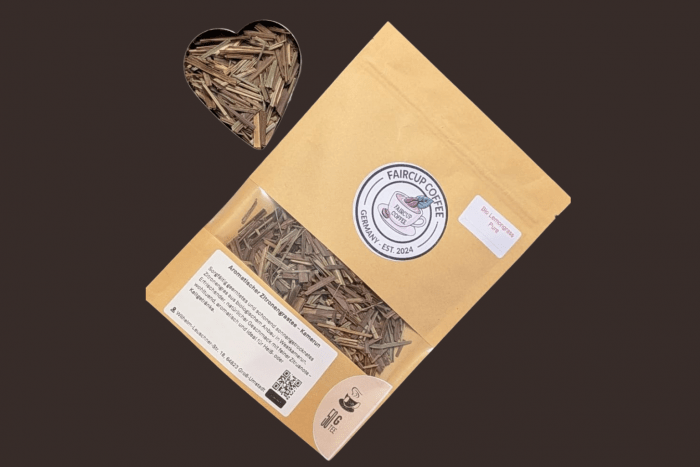 Fair Trade Kaffee in brauner Papierverpackung mit Faircup-Logo und Sichtfenster, daneben herzförmige Schale mit Kaffeebohnen