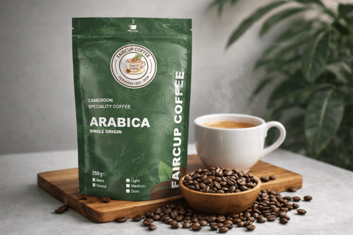 Grüne Packung mit Single origin Kaffee aus Kamerun, daneben Tasse, Holzschale mit Bohnen auf Holzbrett