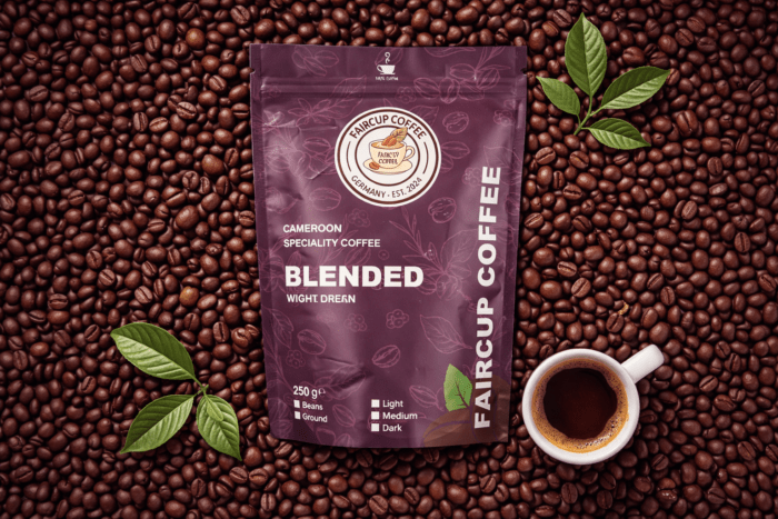 Violette Kaffeepackung Faircup Coffee Blended aus Kamerun auf Kaffeebohnen mit Blättern und Kaffeetasse