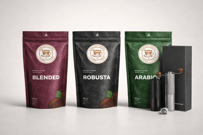 Drei Kaffeebeutel mit den Sorten Blended, Robusta und Arabica neben zwei Handkaffeemühlen und schwarzer Verpackung